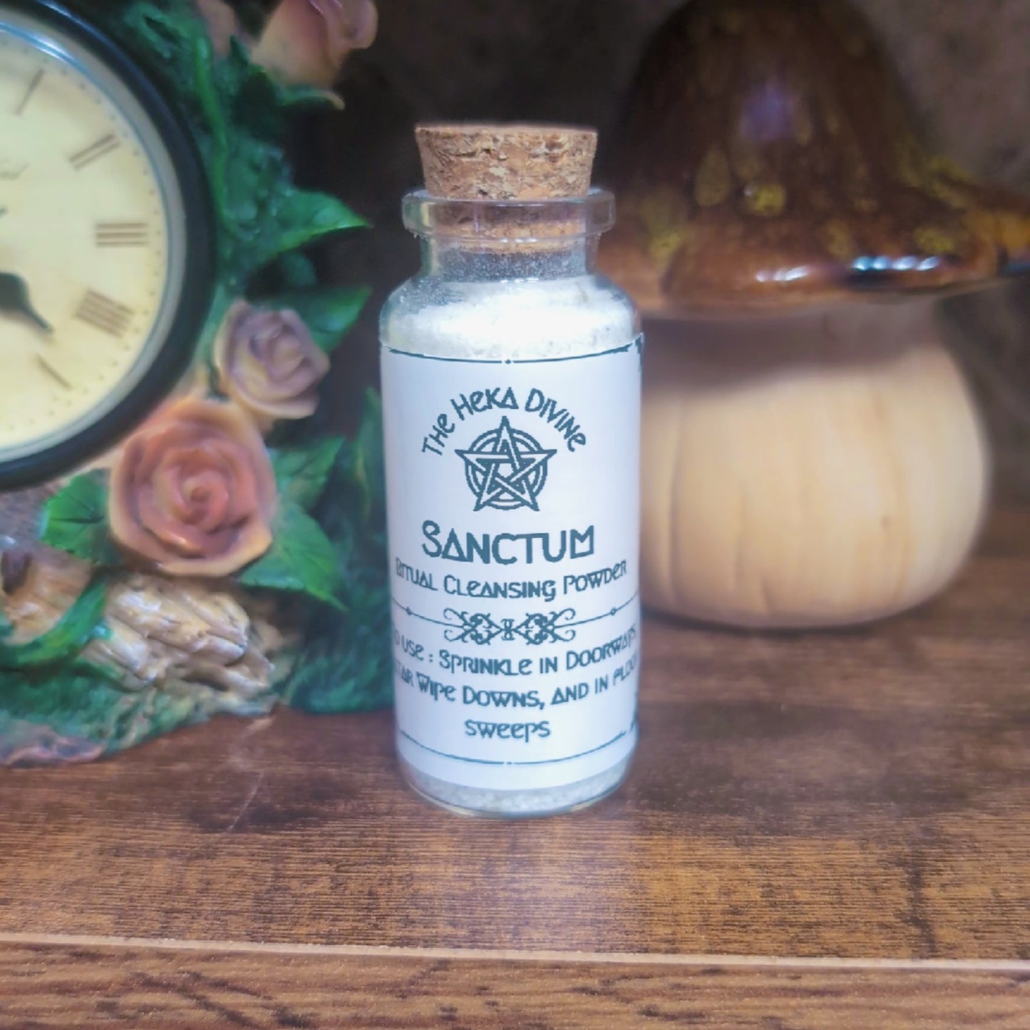 Bottle labeled 'Sanctum' on a wooden surface with decorative items in the background - botanical powder blend inside bottle